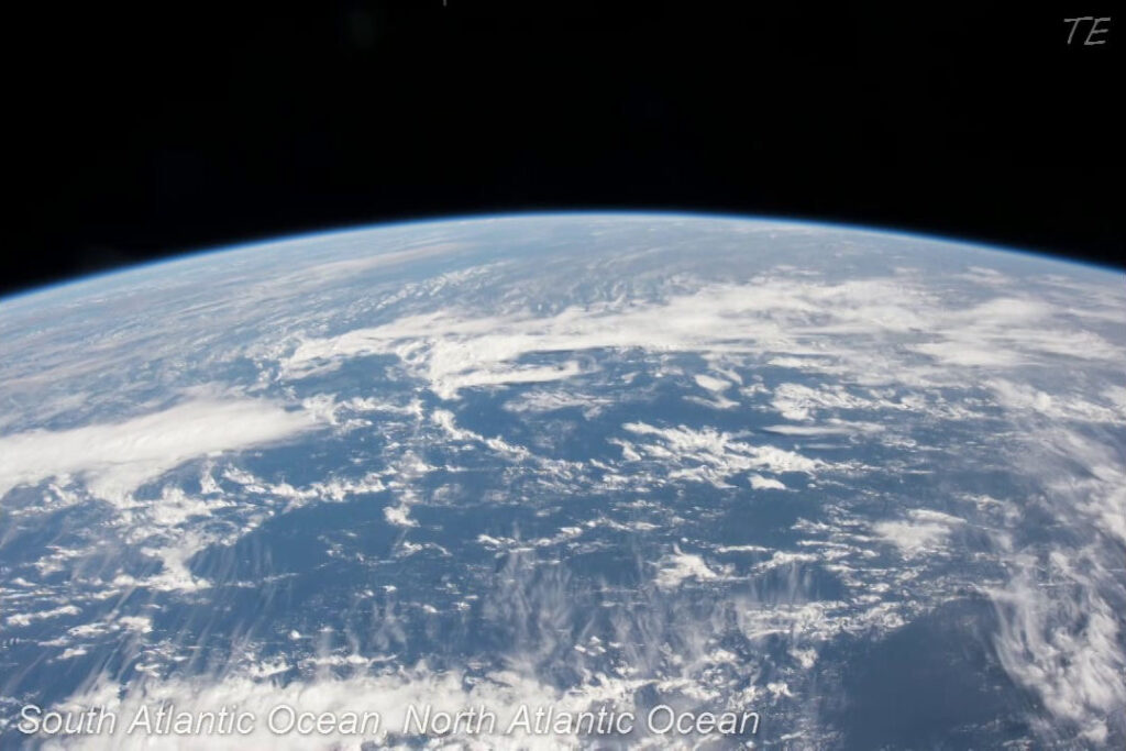 Blick aus der ISS auf den Atlantischen Ozean, bedeckt mit Wolkenformationen, unter einem dunklen Weltraumhintergrund.