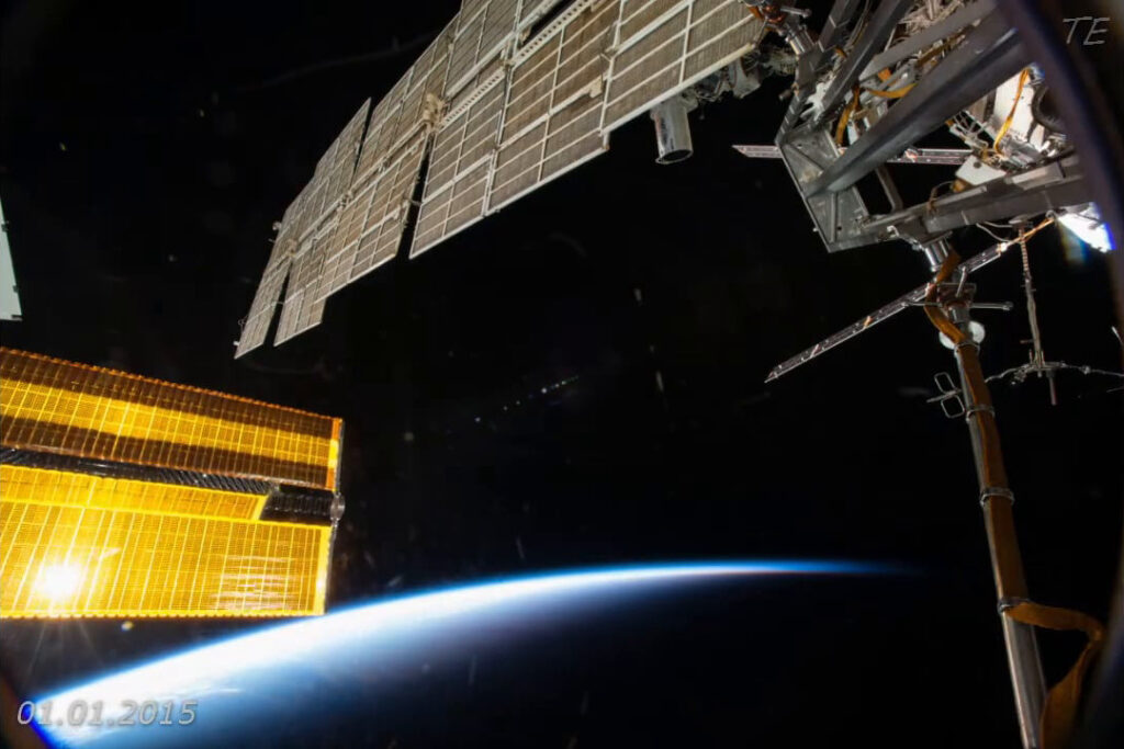 Sonnenkollektoren der ISS vor der Erdkrümmung im Weltall, beleuchtet von Sonnenlicht.