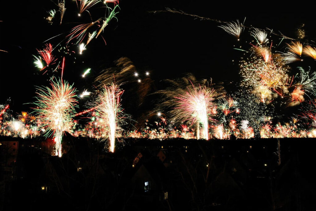 Feuerwerk am Nachthimmel mit bunten Funken in Rot, Grün und Gold.