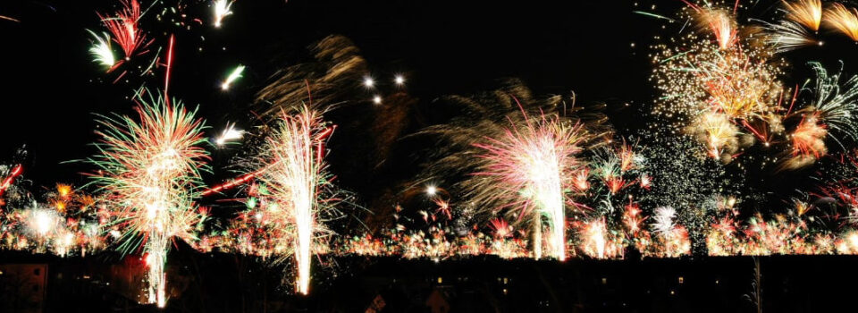 Feuerwerk am Nachthimmel mit bunten Funken in Rot, Grün und Gold.